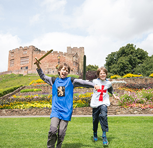 Image shows two boys, wearing chainmail and holding swords, pretending to be Anglo-Saxon soldiers in the grounds of Tamworth Castle